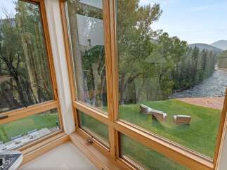 Experience breathtaking views from this stunning home, featuring expansive windows that frame a serene river and lush forest.