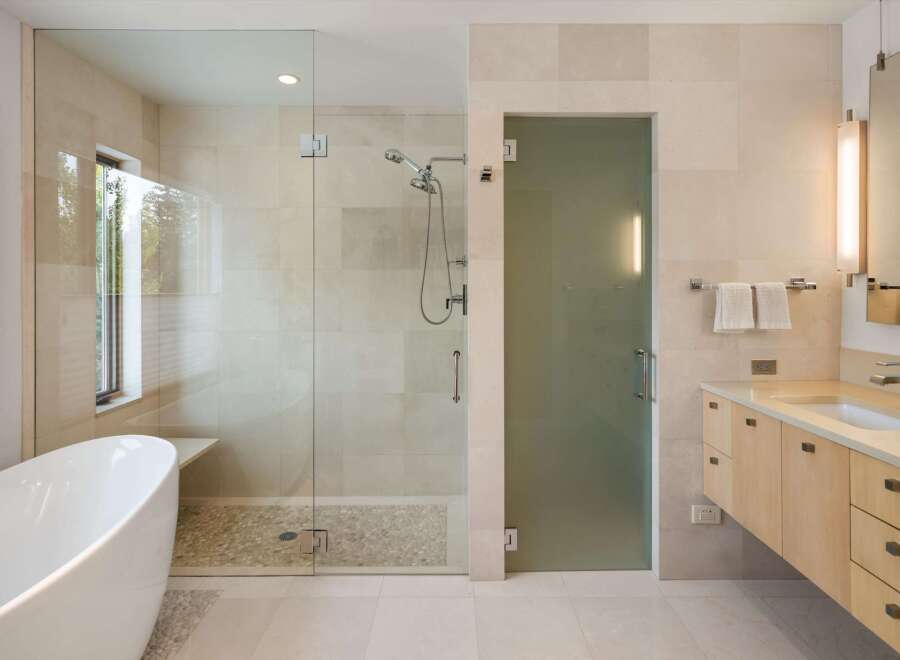 Experience luxury in this modern bathroom featuring a freestanding soaking tub and a spacious glass-enclosed shower with a pebble tile floor.