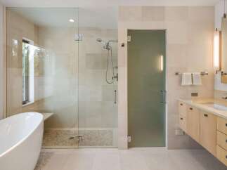 Experience luxury in this modern bathroom featuring a freestanding soaking tub and a spacious glass-enclosed shower with a pebble tile floor.