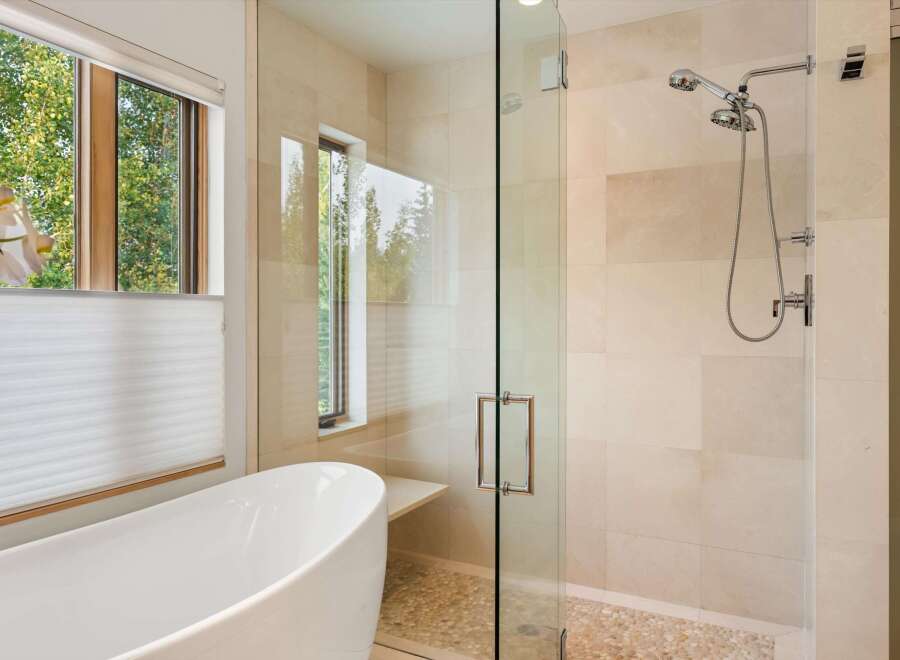 Experience luxury in this modern bathroom featuring a freestanding soaking tub and a spacious glass-enclosed shower with a dual showerhead.