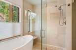 Experience luxury in this modern bathroom featuring a freestanding soaking tub and a spacious glass-enclosed shower with a dual showerhead.