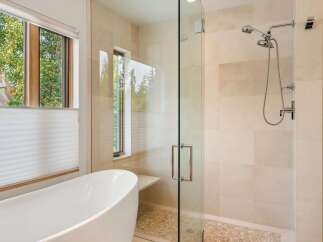 Experience luxury in this modern bathroom featuring a freestanding soaking tub and a spacious glass-enclosed shower with a dual showerhead.