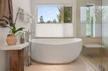 Indulge in ultimate relaxation in this luxurious bathroom, featuring a stunning freestanding bathtub with a picturesque window view of the surrounding nature.
