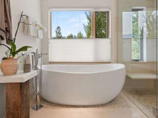 Indulge in ultimate relaxation in this luxurious bathroom, featuring a stunning freestanding bathtub with a picturesque window view of the surrounding nature.