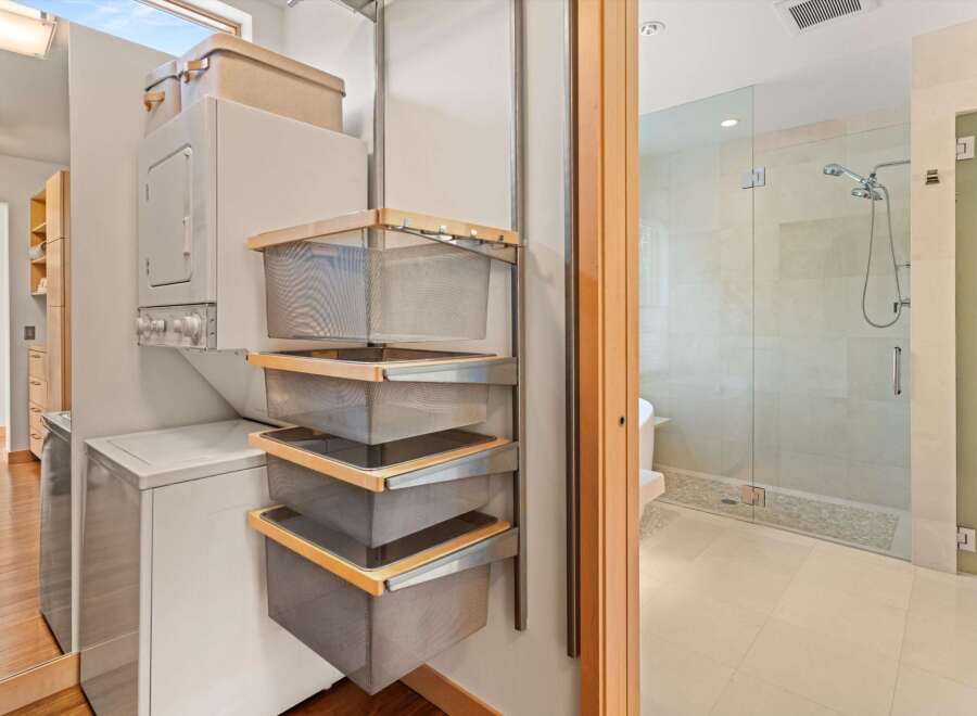 Discover the ultimate in laundry and bathroom convenience with this modern stacked washer/dryer unit and a sleek, glass-enclosed shower.