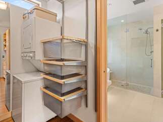 Discover the ultimate in laundry and bathroom convenience with this modern stacked washer/dryer unit and a sleek, glass-enclosed shower.