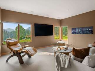 Experience breathtaking mountain views from this luxurious living room, featuring a comfortable leather recliner and a large flat-screen TV.