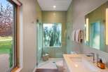 Experience modern luxury in this stunning bathroom featuring a walk-in shower with elegant green mosaic tile and a frosted glass window offering a serene view.