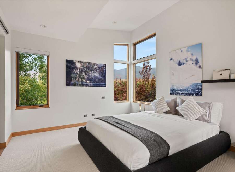 Experience modern luxury in this stunning bedroom, featuring expansive windows that flood the space with natural light and offer breathtaking mountain views.
