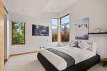 Experience modern luxury in this stunning bedroom, featuring expansive windows that flood the space with natural light and offer breathtaking mountain views.