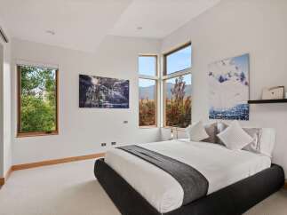 Experience modern luxury in this stunning bedroom, featuring expansive windows that flood the space with natural light and offer breathtaking mountain views.