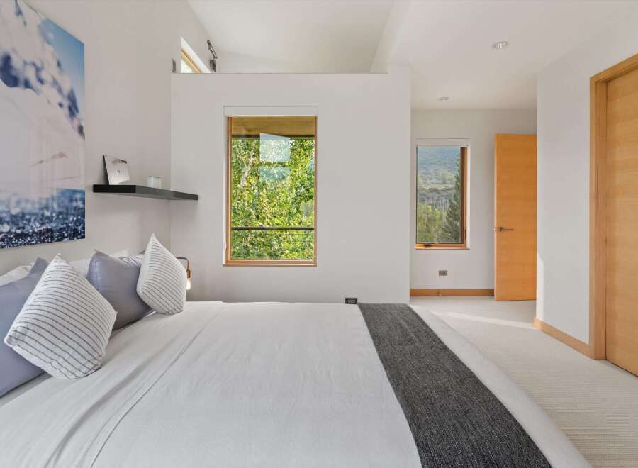 Experience serene mountain living in this modern bedroom, featuring a comfortable king-sized bed adorned with plush pillows and a stylish grey throw.
