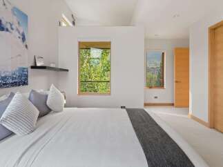 Experience serene mountain living in this modern bedroom, featuring a comfortable king-sized bed adorned with plush pillows and a stylish grey throw.
