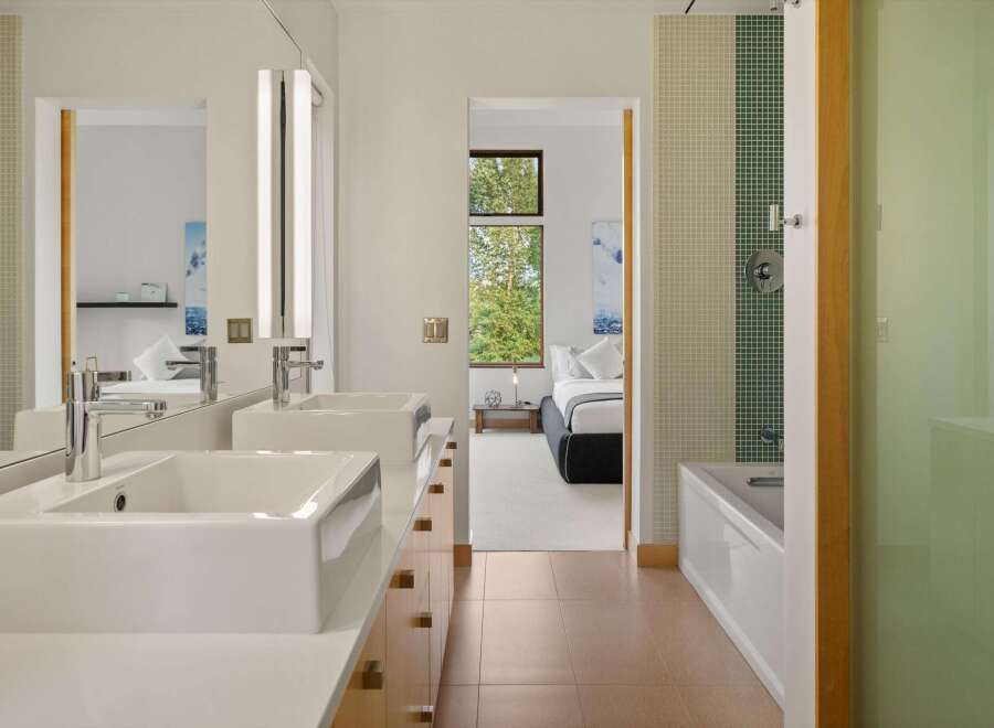 Experience modern luxury in this stunning bathroom featuring dual vessel sinks atop a sleek vanity with ample storage.