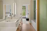 Experience modern luxury in this stunning bathroom featuring dual vessel sinks atop a sleek vanity with ample storage.