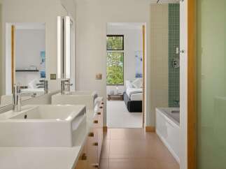 Experience modern luxury in this stunning bathroom featuring dual vessel sinks atop a sleek vanity with ample storage.