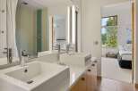Experience modern luxury in this stunning bathroom featuring dual vessel sinks atop a sleek white countertop and complemented by a vibrant mosaic tile shower.
