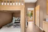 This cozy bedroom features a rustic wooden bunk bed with plush bedding and decorative pillows, perfect for accommodating guests.