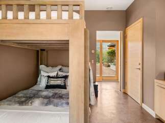 This cozy bedroom features a rustic wooden bunk bed with plush bedding and decorative pillows, perfect for accommodating guests.