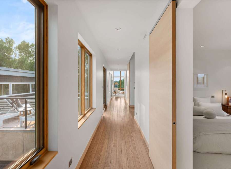 Experience modern living in this stunning home featuring a long, bright hallway with rich hardwood floors and large windows that flood the space with natural light.