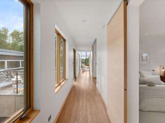 Experience modern living in this stunning home featuring a long, bright hallway with rich hardwood floors and large windows that flood the space with natural light.