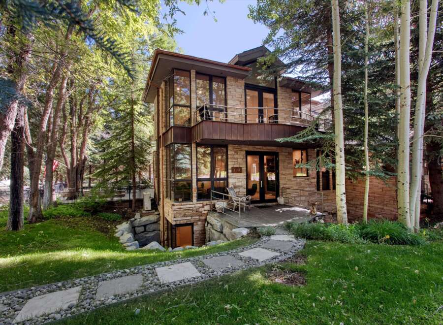 Nestled amidst lush greenery and mature trees, this modern stone home offers a unique architectural design.