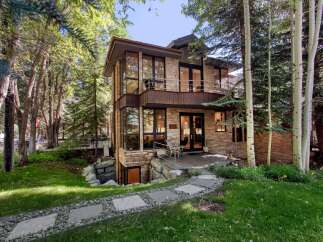 Nestled amidst lush greenery and mature trees, this modern stone home offers a unique architectural design.