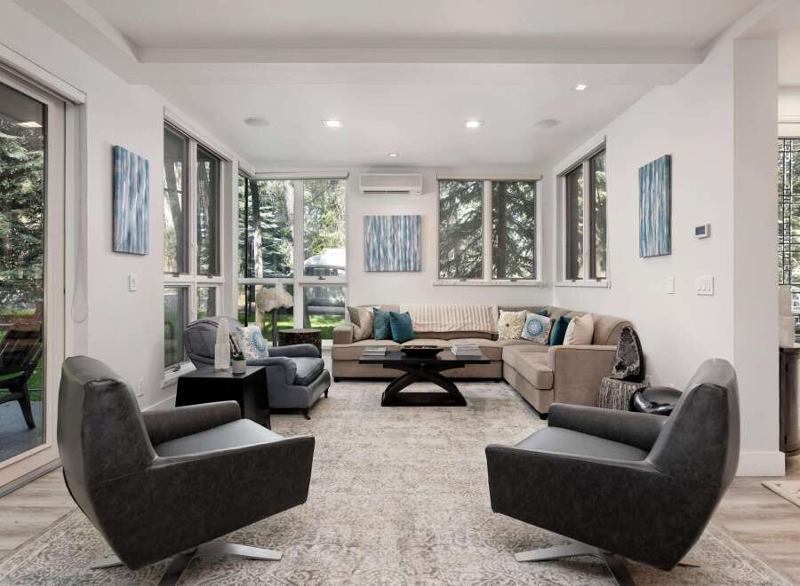 Experience modern living in this spacious living room, featuring a large sectional sofa and comfortable armchairs perfect for relaxation.