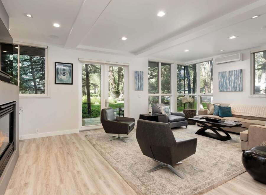Experience modern living in this bright and airy living room, featuring a sleek fireplace and expansive windows that flood the space with natural light.