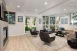Experience modern living in this bright and airy living room, featuring a sleek fireplace and expansive windows that flood the space with natural light.