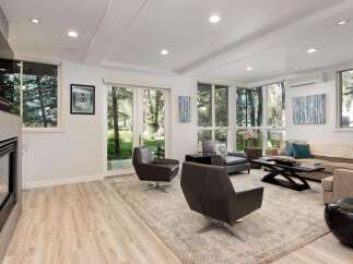 Experience modern living in this bright and airy living room, featuring a sleek fireplace and expansive windows that flood the space with natural light.