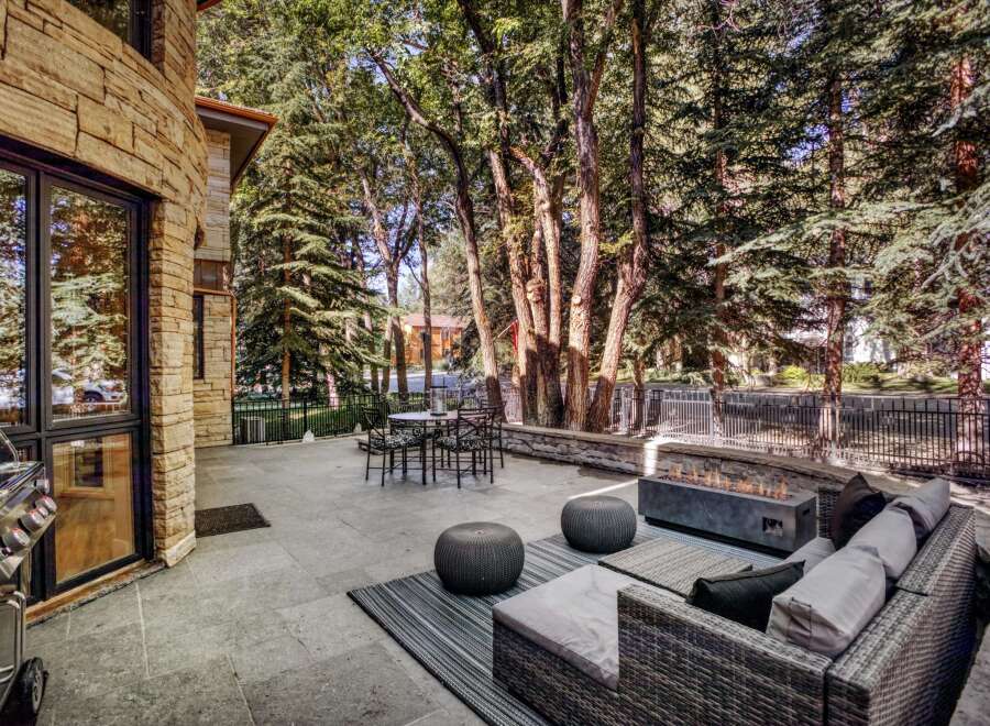Experience luxurious outdoor living with this stunning patio featuring a modern gas fire pit and comfortable seating.
