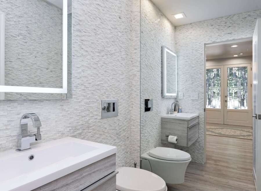 Experience modern luxury in this stunning bathroom, featuring sleek vanities and a striking stacked stone accent wall.