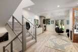 Step into this modern living space featuring a sleek staircase with cable railings and a cozy fireplace area.
