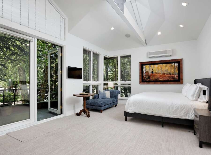 Experience luxurious living in this stunning bedroom featuring a spacious king-sized bed and a cozy blue chaise lounge.