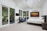 Experience luxurious living in this stunning bedroom featuring a spacious king-sized bed and a cozy blue chaise lounge.