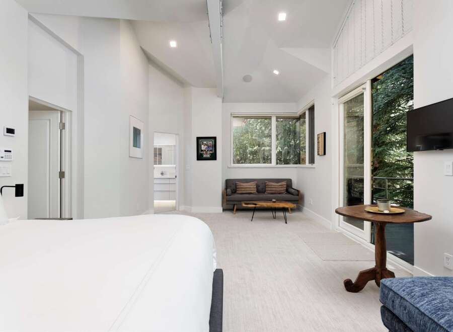 Experience luxury living in this spacious bedroom featuring a comfortable king-sized bed and a private balcony with stunning forest views.
