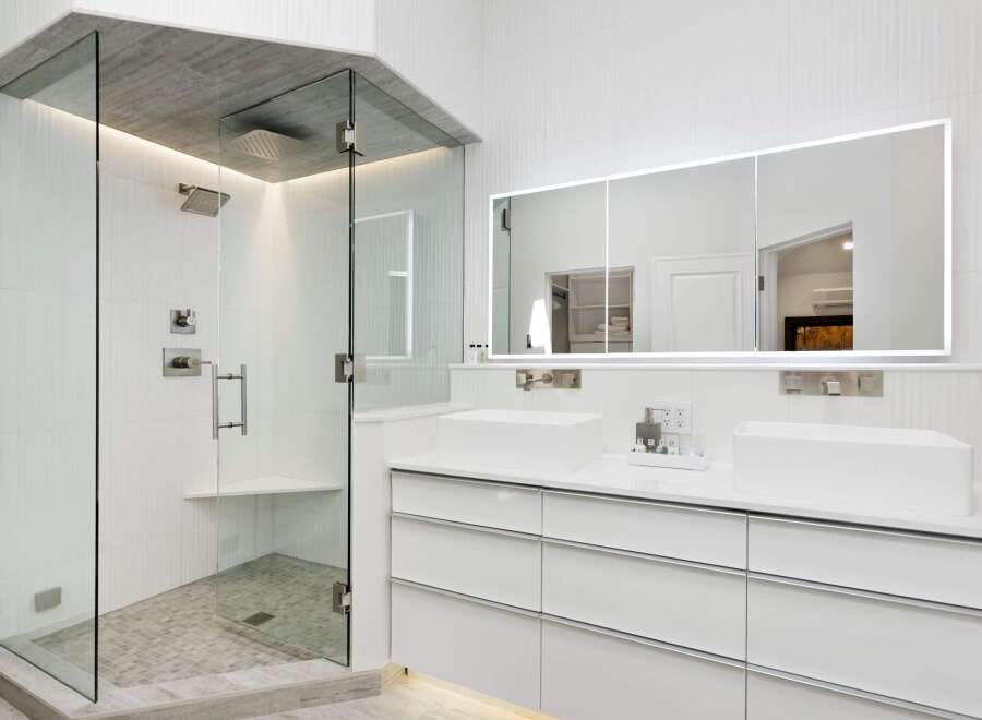 Experience luxury in this modern bathroom featuring a spacious glass-enclosed shower with a rainfall showerhead and a built-in bench.