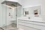 Experience luxury in this modern bathroom featuring a spacious glass-enclosed shower with a rainfall showerhead and a built-in bench.