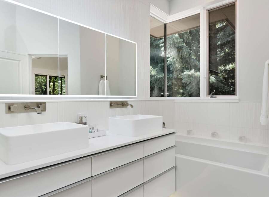 Experience modern luxury in this stunning bathroom featuring dual vessel sinks atop a sleek white vanity with ample storage.
