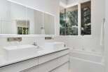 Experience modern luxury in this stunning bathroom featuring dual vessel sinks atop a sleek white vanity with ample storage.