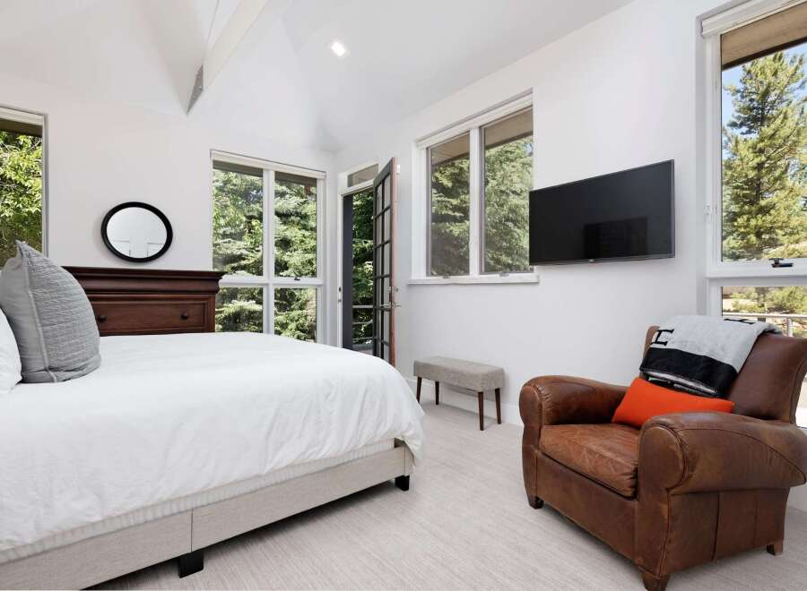 Experience luxurious mountain living in this stunning bedroom featuring a plush king-sized bed and a cozy leather armchair.