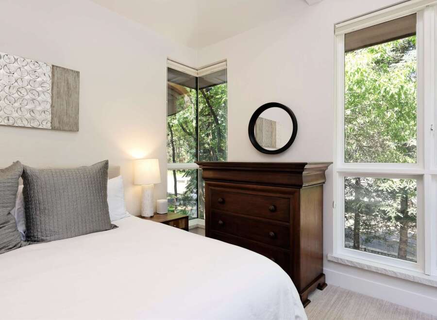 Experience serene living in this beautifully appointed bedroom, featuring a plush bed adorned with elegant grey pillows.