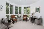 This bright and airy room features a curved wall of windows offering serene views of the surrounding trees.