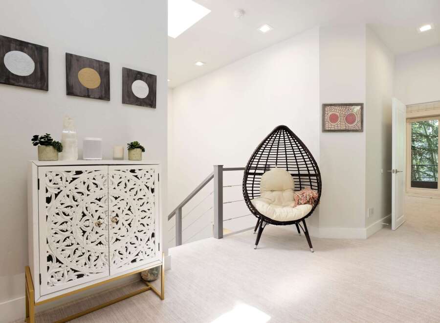 Discover modern elegance in this inviting hallway, featuring a striking white carved cabinet adorned with decorative accents and a unique egg-shaped chair perfect for relaxation.