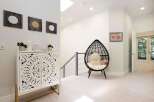 Discover modern elegance in this inviting hallway, featuring a striking white carved cabinet adorned with decorative accents and a unique egg-shaped chair perfect for relaxation.