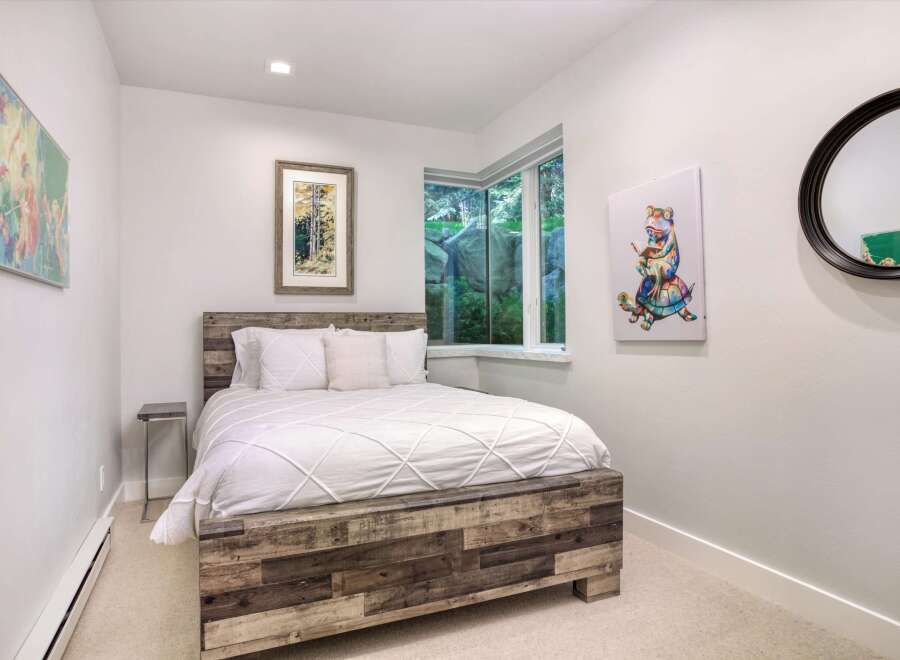 This charming bedroom features a rustic wooden bed frame complemented by crisp white linens, creating a cozy and inviting atmosphere.