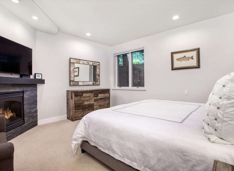Experience ultimate comfort in this master bedroom, featuring a cozy fireplace and a large flat-screen TV for entertainment.