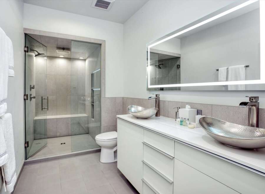 Experience modern luxury in this stunning bathroom featuring a spacious walk-in shower with sleek tile work and a built-in bench.