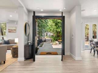 Step into this stunning entryway, where an open-concept design seamlessly connects the interior living spaces with the lush outdoor patio.